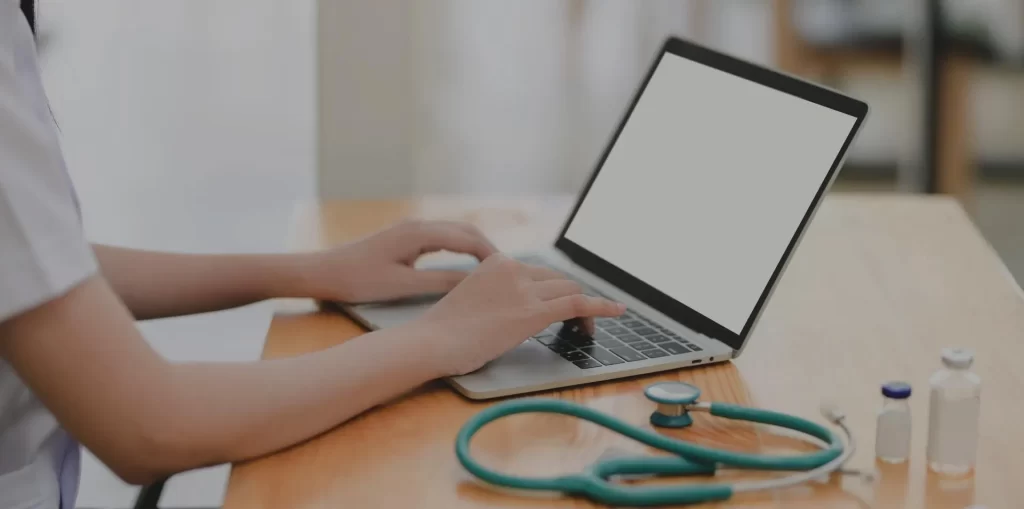 Doctor working on a laptop with stethoscope placed on a side